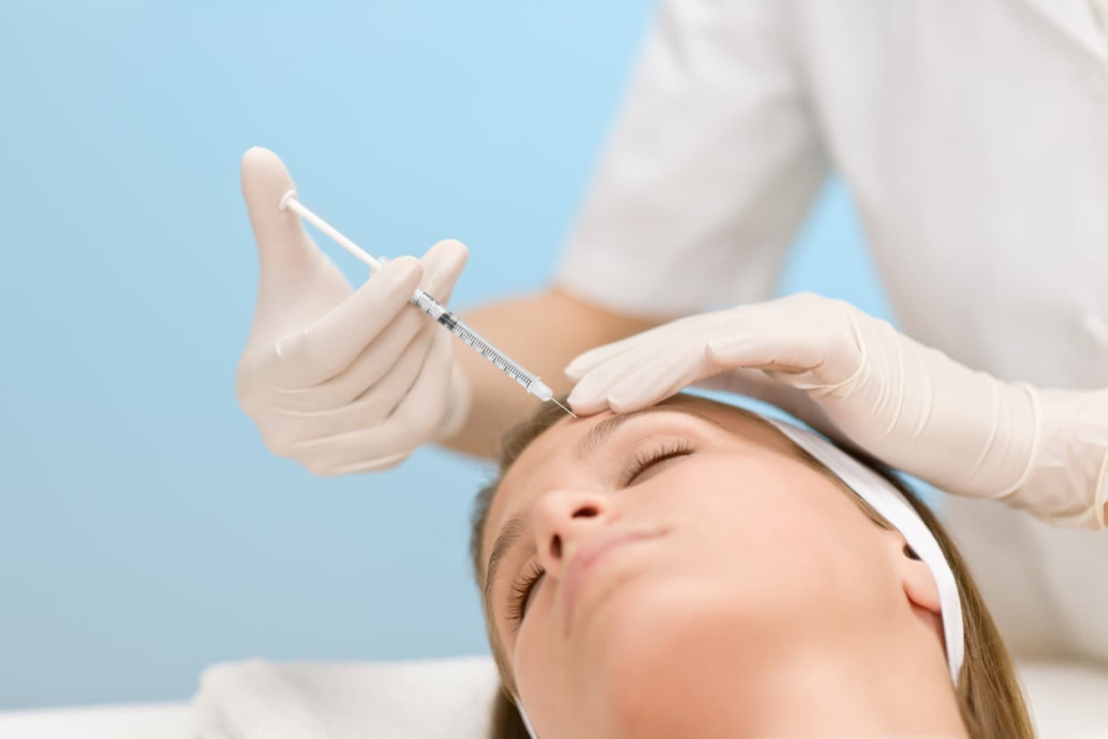 Gloved practitioner administering a cosmetic injection to a womans forehead at a med spa