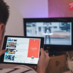 man browsing tablet sitting in front of TV