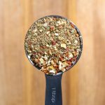 a metal spoon filled with granola on top of a wooden table