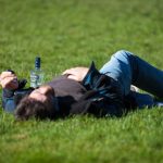 a man laying in the grass with a bottle of beer