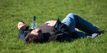 a man laying in the grass with a bottle of beer