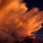 Wind blown cloud tops in the setting sun.