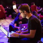 man using laptop in front of brown chair