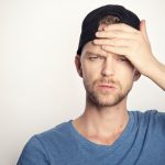 man in blue crew neck shirt covering his face