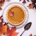 a pie sitting on top of a white table next to leaves