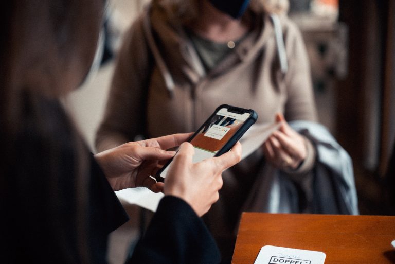 woman in brown coat holding black smartphone