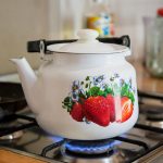 white and red strawberry print ceramic teapot on stove