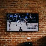 black flat screen tv mounted on brown brick wall