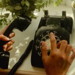 person holding black rotary telephone