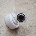 white surveillance camera hanging on wall