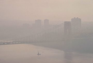 a foggy view of a bridge over a body of water