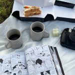 A picnic with a book and coffee on a blanket