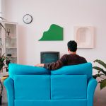 man in black and red jacket sitting on orange sofa