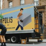 woman in blue shorts and black boots standing beside yellow and white truck during daytime