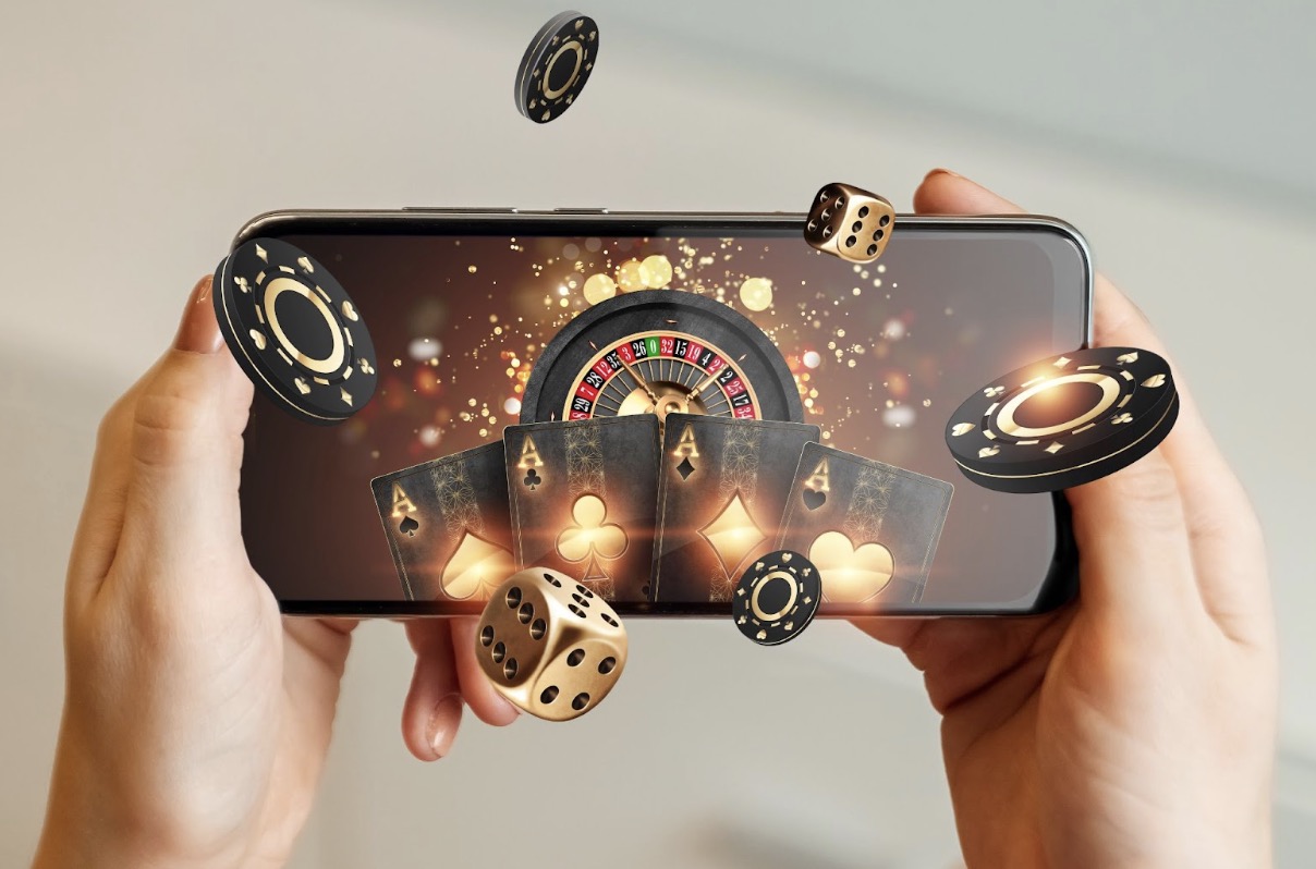 Hands holding a smartphone displaying a roulette and casino elements flying out of the screen.