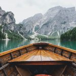 brown wooden boat moving towards the mountain