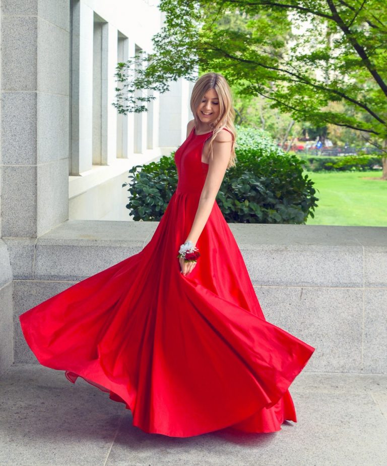 woman in red sleeveless dress standing on gray concrete floor during daytime