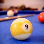 a pool table with a pool ball and cues