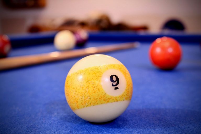 a pool table with a pool ball and cues