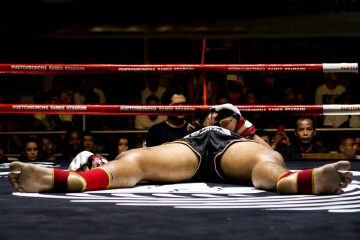 woman in black and white sports bra and black shorts lying on floor