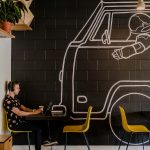 man wearing headphone using laptop while sitting beside table inside cafe