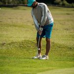 man in white long sleeve shirt and red cap playing golf during daytime