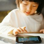 woman in white long sleeve shirt holding black smartphone