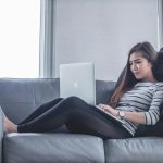 woman sitting on sofa while using MacBook Pro