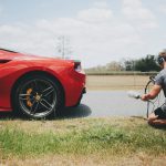 man behind car holding microphone measuring sound