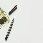 gray pen beside coins on Indian rupee banknotes