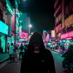 man in black hoodie walking on street during night time