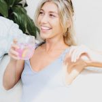 woman in white tank top holding clear drinking glass