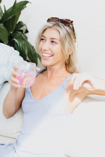 woman in white tank top holding clear drinking glass