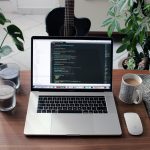 macbook pro beside white ceramic mug on brown wooden table