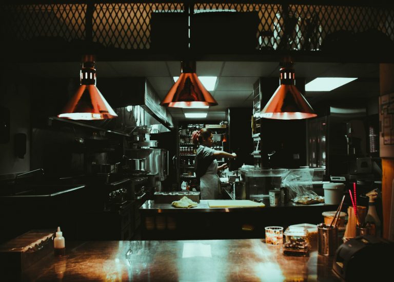 woman standing near three red pendant lamps