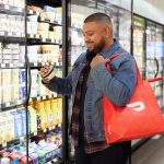 male browsing refrigerated goods at store with DoorDash bag