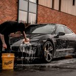 man in black t-shirt and black pants doing water splash on black coupe during daytime