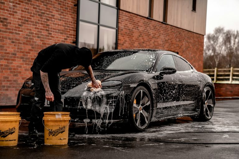 man in black t-shirt and black pants doing water splash on black coupe during daytime