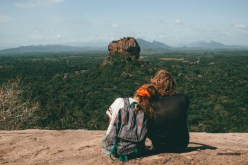 man and woman sitting beside cliff