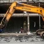 a large yellow excavator sitting in front of a building