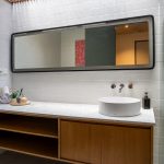 A bathroom with a large mirror and a sink