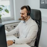 a man wearing a headset sitting in front of a computer