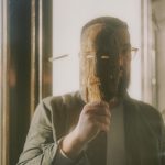 man in gray long sleeve shirt holding brown wooden stick