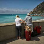 man and woman standing beside concrete seawall looking at beach