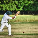 man in white pants and blue baseball mitt holding baseball bat during daytime