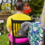 a dog sitting on a chair in front of a woman