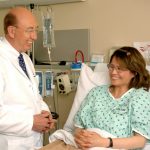 woman in teal scrub suit sitting beside man in white medical scrub suit