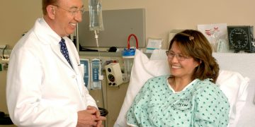 woman in teal scrub suit sitting beside man in white medical scrub suit