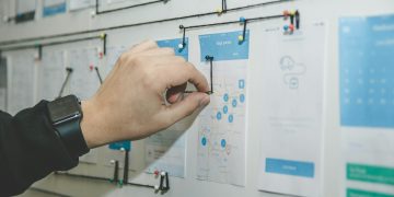 person working on blue and white paper on board