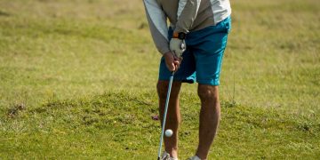 man in white long sleeve shirt and red cap playing golf during daytime